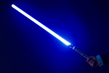 Naklejka premium Close-up of blue colored illuminated laser sword with grip against black background. Photo taken January 25th, 2023, Zurich, Switzerland.