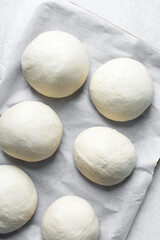 Fototapeta na wymiar Bread bun dough that has doubled in size, dough that has risen, proofed dough on parchment lined baking sheet