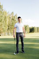 golfer stands with a golf club on a green field. High quality photo