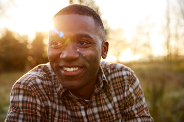 Head And Shoulders Portrait Of Smiling Man Outdoors In Countryside With Flaring Evening Sun