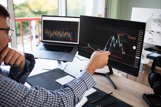 Cropped photo broker, a stock market investor, looks at trading charts using a computer, analyzing investment strategy, financial risks on cryptocurrency stock market graph on pc screen