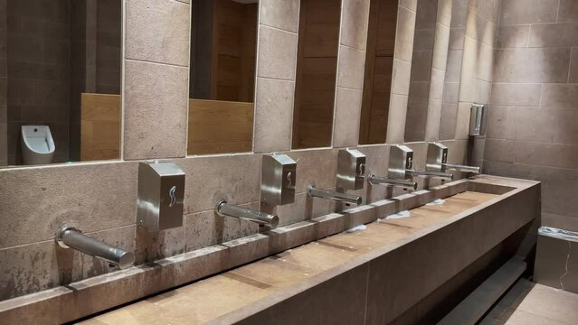 Row of automated silver taps inside a modern public bathroom