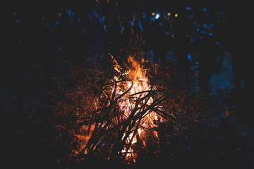Fototapeta na wymiar Orthodox Christmas celebration in Montenegro and Serbia, process of burning the Badnjak, fire with oak tree logs and branch during Badnji dan, the Christmas Eve. Bonfire, church and people around