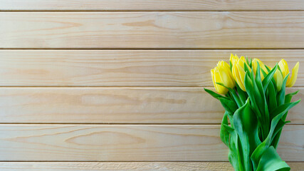 Tulips for Mother's Day, Valentine's Day, Birthday. Bouquet of yellow tulips on a wooden background with copy space.