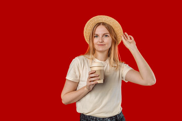 Obraz na płótnie Canvas Young woman wearing a summer hat with a paper eco coffee to go on an red background. High quality photo