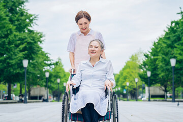 車椅子の女性と介護するエプロン姿の女性