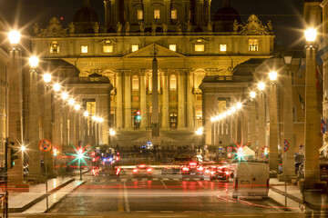 Fototapeta na wymiar View of Illuminated Saint Peter`s Basilica and Street Via della Conciliazione at sunset with cars and traffic on the street. Rome, Italy Europe