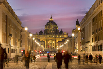 Fototapeta premium View of Illuminated Saint Peter`s Basilica and Street Via della Conciliazione at sunset with people on the street. Rome, Italy Europe