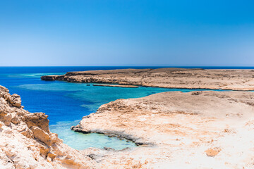 Sandy and rocky coast with blue color of water. Desolate beach on the coast shore of Red Sea. Ras Muhammad in Egypt at the southern extreme of the Sinai Peninsula. Travel concept