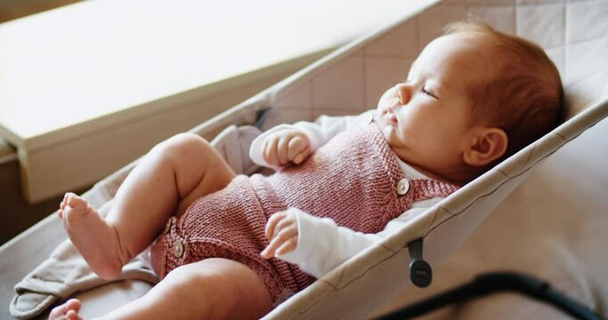 Little baby girl lies on a swing or deck chair and rides. child portrait. side view. High quality 4k footage