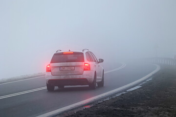 Ruch pojazdów w gęstej mgle na drodze wieczorem. Niebezpiecznie