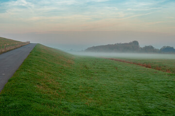 Ground fog in the dusk of the typical dike landscapes of East Frisia in the tourist resort of Norddeich directly at the north sea 
