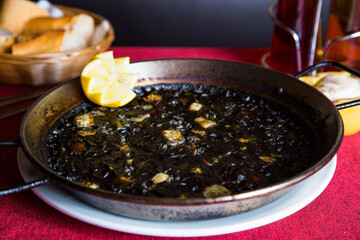 Black paella with squid and pistachio pesto. Tapa paella typical recipe from the Spanish Mediterranean coast.