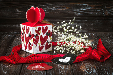 A gift for Valentine s Day. Festive box with hearts, cards, gypsophila flowers and red ribbon on a...