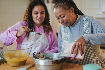 African mother and adult daughter having fun bakeing together at home