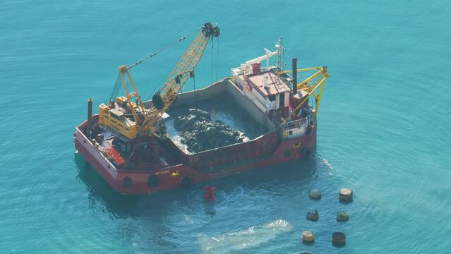 A boat is dredging the sea. Dredging is the removal of sediments and debris from the bottom of lakes, rivers, harbors, and other water bodies. 