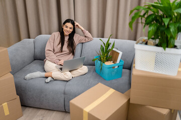 Obraz premium pretty happy woman moving in to new apartment with boxes
