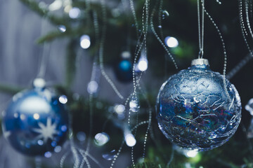 Close up of blue and silver glass toys on Christmas tree with bokeh