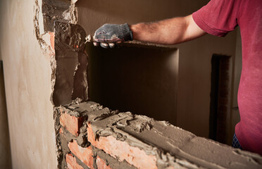 Close up of man hand in work glove laying brickwork in building under construction. Male worker...