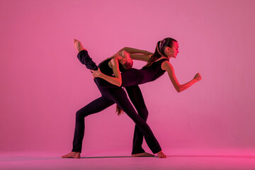 ?hildren dancing. Group of children, little girls in sportive style clothes dancing in choreography class isolated on background in neon light.