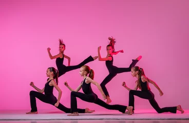 Fotobehang Dansschool ballet girls with long loose hair in black tight-fitting suits dancing on a red background