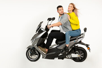 Obraz na płótnie Canvas young attractive couple riding an electric motorbike scooter happy having fun together