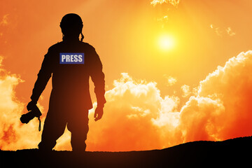 Photojournalist silhouette documenting war or conflict. Photojournalist at sunset. War, army,...