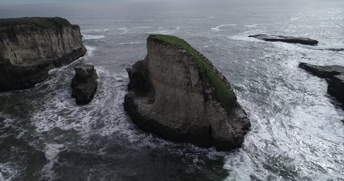 Shark Fin Cove Beach with a Towering rock and Sea Cave. California. Pacific Ocean Waves. Island. Drone