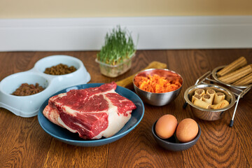 Dry food for dogs based on raw meat and snacks copy space, indoors. Pet food and its ingredients on wooden table. Dog nutrition advertisement concept. fresh meal for pet dog