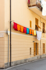 Traditional architecture of an old Italian village, facade of a building with colored walls and dangling clothes on a clothesline