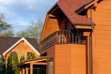 Modern wooden eco house villa facade luxury big house. Timber cottage with with green lawn water sprinkler, paved footpath and blue sky background. Landscaping design, garden watering and maintenance