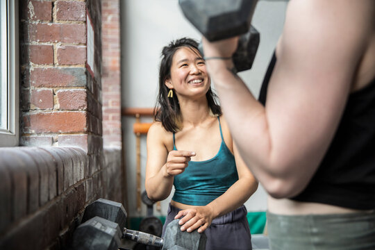 Happy woman working out with friend in gym