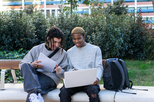 Positive multiethnic students working on homework in park