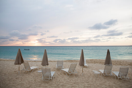 Scenic view of parasols and lounge chairs at beach against cloudy sky