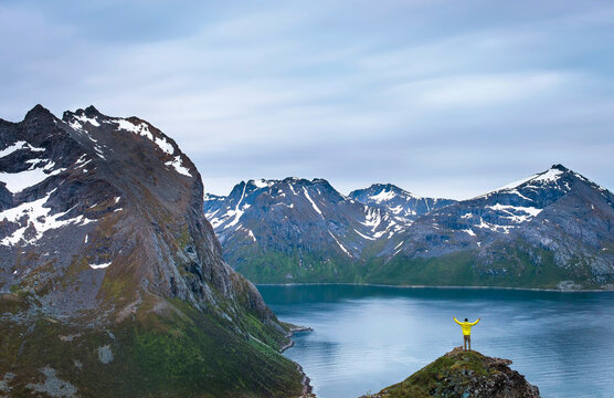Young male hiker stands at the top of a mountain near Troms&Atilde;&cedil; Norway overlooking fjords