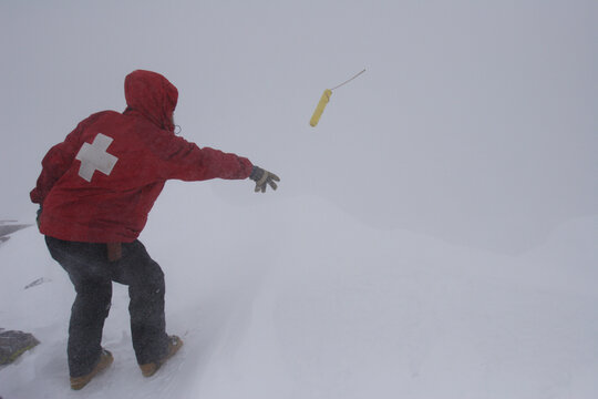 A ski patroller throws a stick of dynamite while on his snow safety route. Ski patrollers throw dynamite to trigger potential av