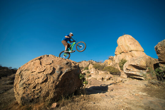 A man performs trial bike standing on a rock at El Diente, Jalisco, Mexico.