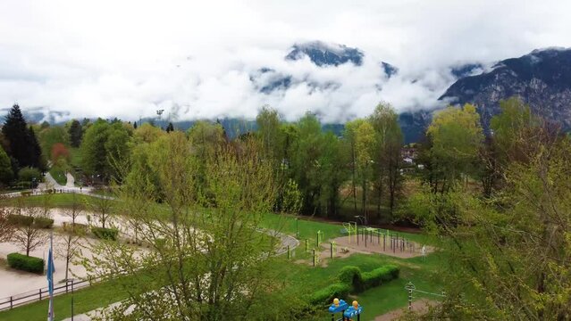 Drone footage aerial view of the levico terme town in trentino (Trento) city surrounded by mountains with fog from above