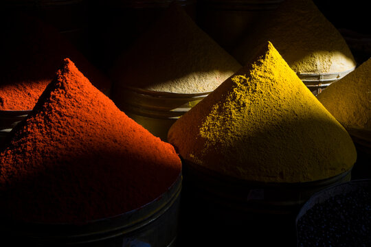 Neat mounds of colorful spices on sale in a storefront.