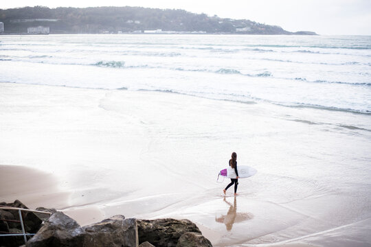 Woman Surfing on a stormy day at Hendaye Plage on the border of France