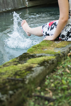 Woman splashing water with her leg at Eisbach Riverbank