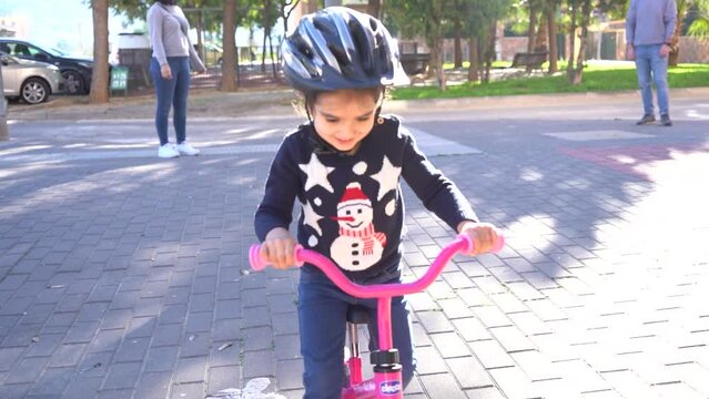 Young girl kid learning to ride her bike for the first time in slow motion.
