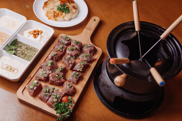 Photo of an elegant fondue. With bowls of sauces, seasoned meats, served with a tomato rostie. Stylish photo for restaurants