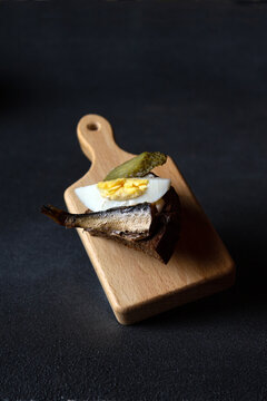 sandwich with smoked sardine on a wooden board on a dark background, flying food