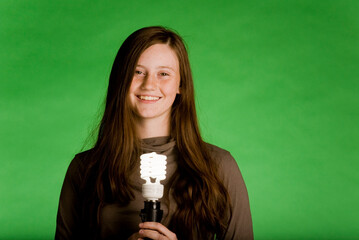 Girl holding an eco friendly lightbulb in front of a green background.