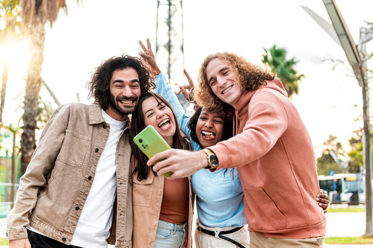 Multicultural men and women taking selfie outside in the city - Happy milenial friendship and life style concept on young multiracial best friends having fun together in a spring day.