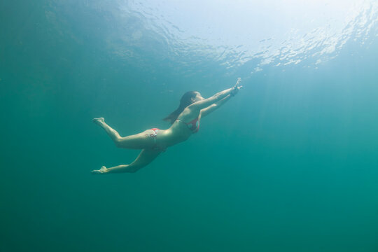 one girl dives in the water wearing a red bikini with white dots. Tamaulipas, Mexico.