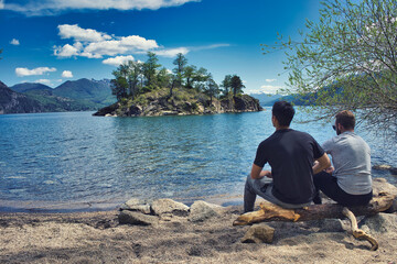 2 men sitting contemplating a small island in the middle of a lake in Patagonia.