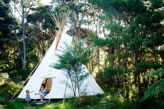 A young woman receives wildflowers gathered by her daughter while ti-pi camping in the forest near Raglan, New Zealand.