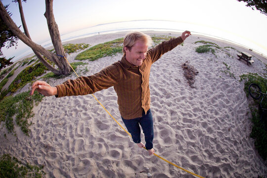 A Man Slacklining at the beach.